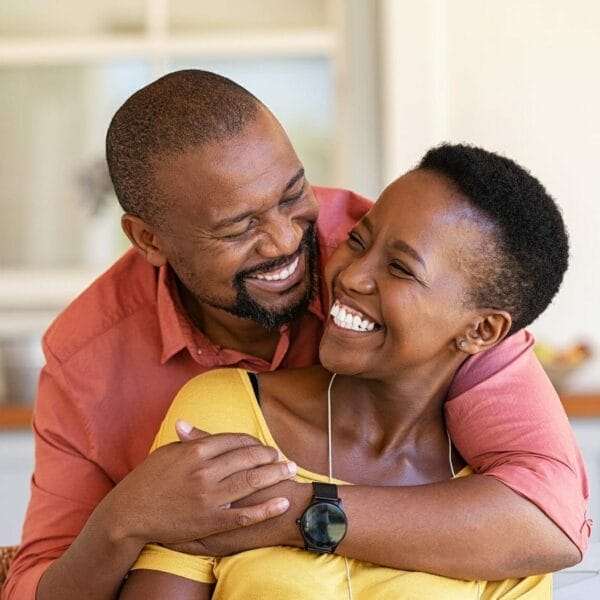 Mature Black Couple Embracing On Sofa While Looking To Each